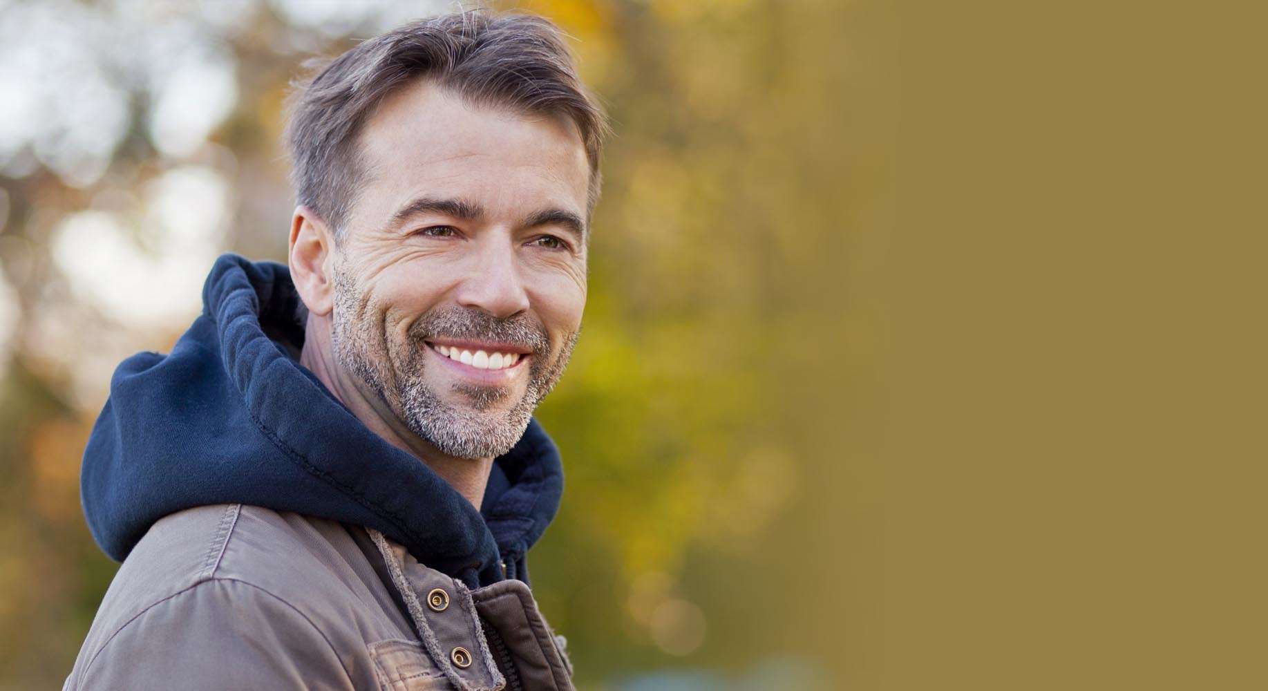 Smiling man wearing a hooded jacket in nature