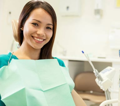 Smiling patient in dental clinic with a dental bib.