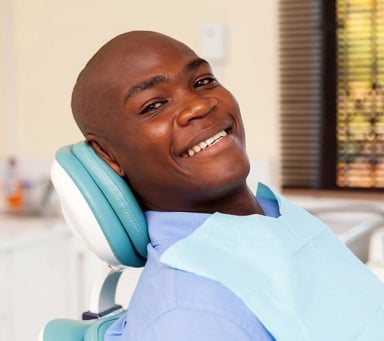 Smiling male dentist in office with patient chair