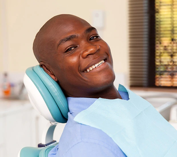 Smiling male dentist in office with patient chair