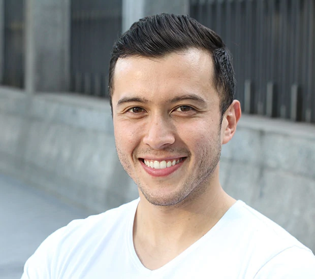 Smiling man with short hair in a white shirt.