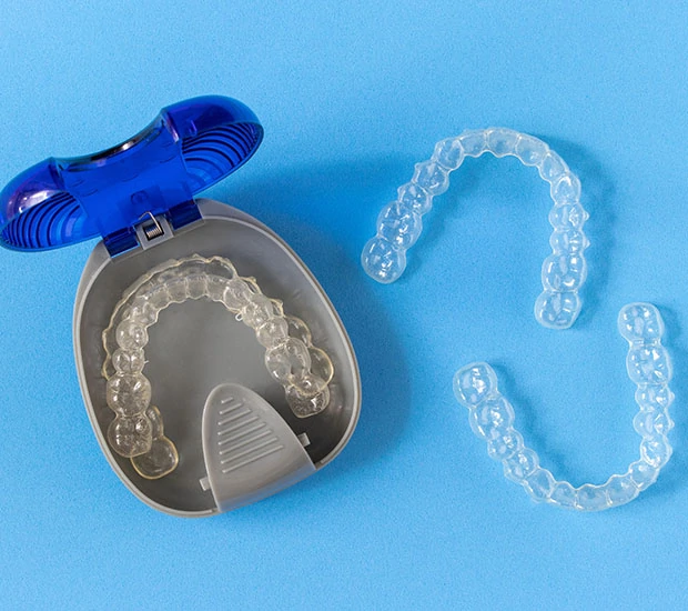 Clear dental aligners in case on blue background