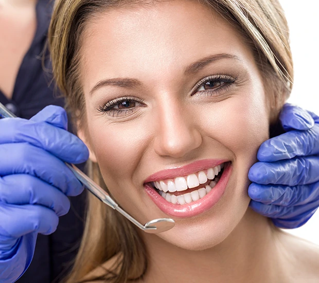 A dentist performing oral examination on a smiling patient.