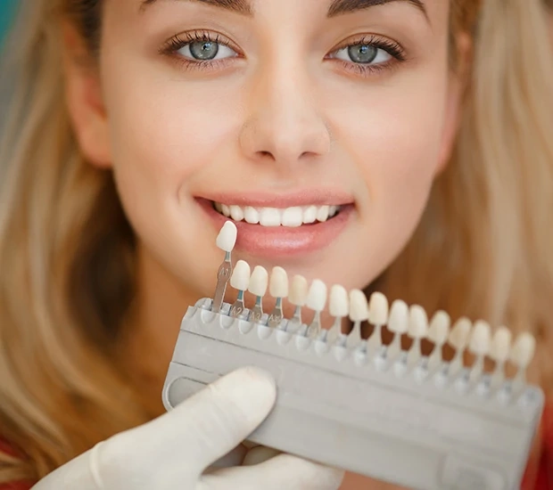 Woman displaying teeth shade guide during dental consultation